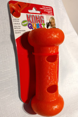 Orange plastic dumbbell with holes for treats to be stuffed into.