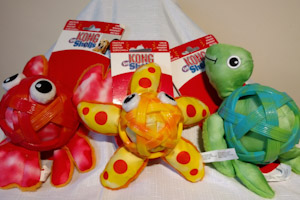 Three dog toys: one red lobster soft toy with red lattice covering body, one yellow starfish with yellow lattice covering body and one green turtle with red lattice covering body.