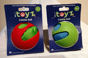 Two Crinkle Balls in their packaging.  One ball is a green crinkly ball with a red rubber outer shell.  The other is a blue crinkly ball with a green rubber outer shell