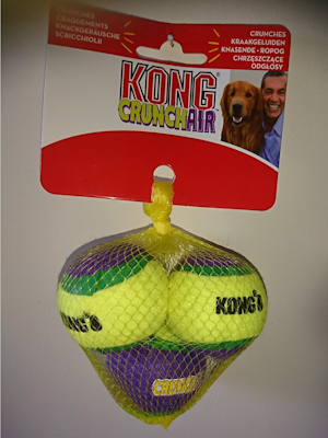 Yellow net containing three Kong CrunchAir Small Balls which are striped yellow, green and purple.