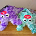 One purple and one turquoise soft toy starfish with large eyes